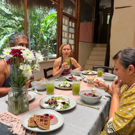 Guests sharing a meal at a long table at Alma Chakana, jungle visible through the windows