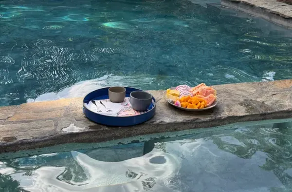A tray of tea and a plate of fresh fruit resting on the stone edge of the pool at Alma Chakana