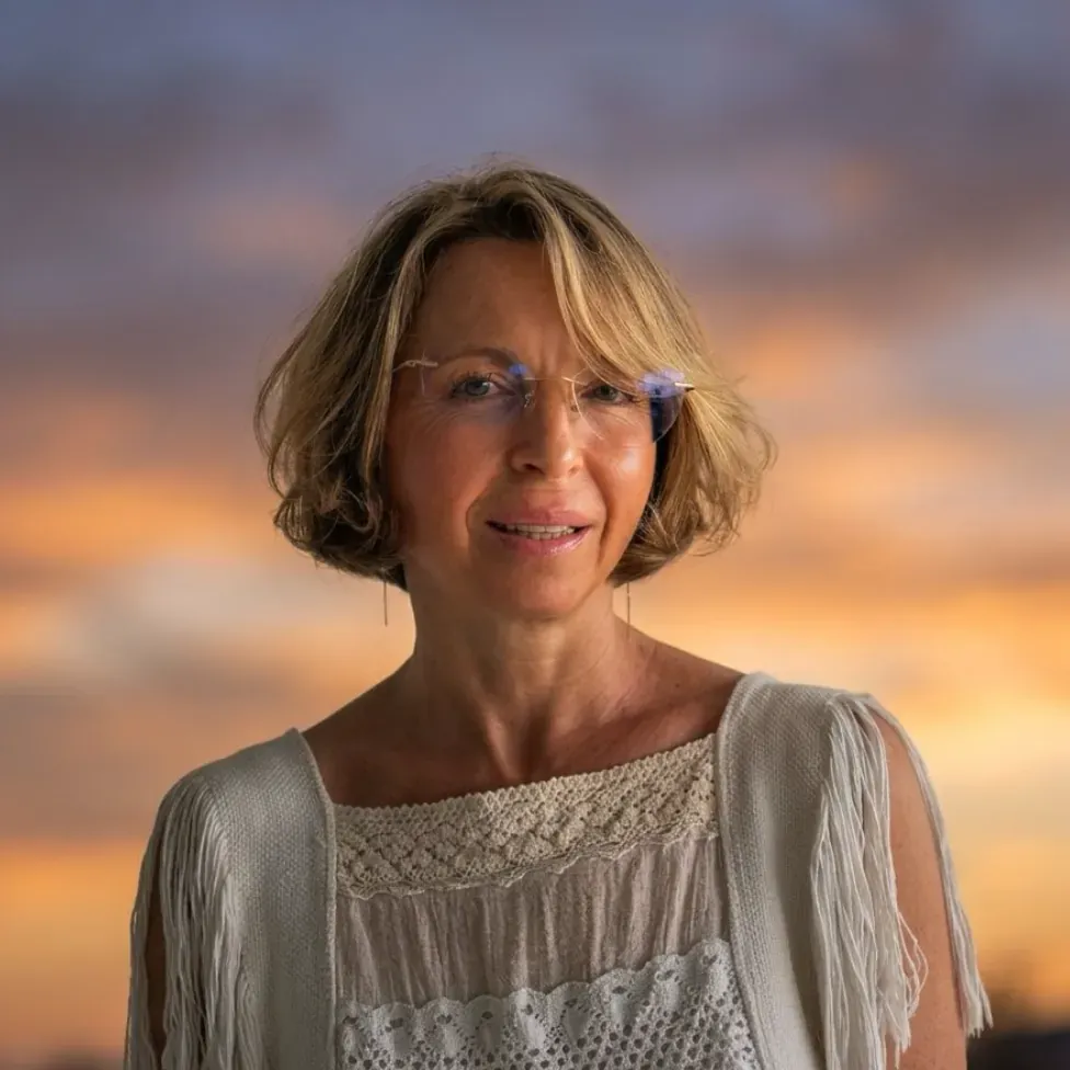 Lena, a facilitator at Compassion Retreats, photographed against a sunset sky