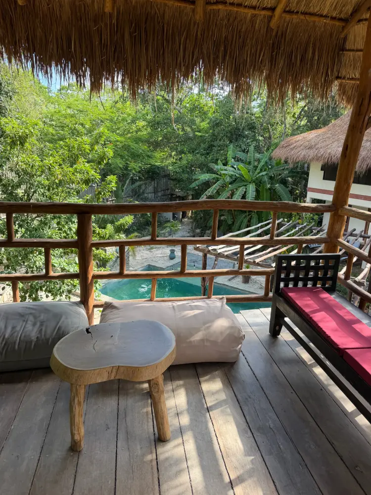 A shaded jungle deck with a small turquoise pool framed by tropical foliage