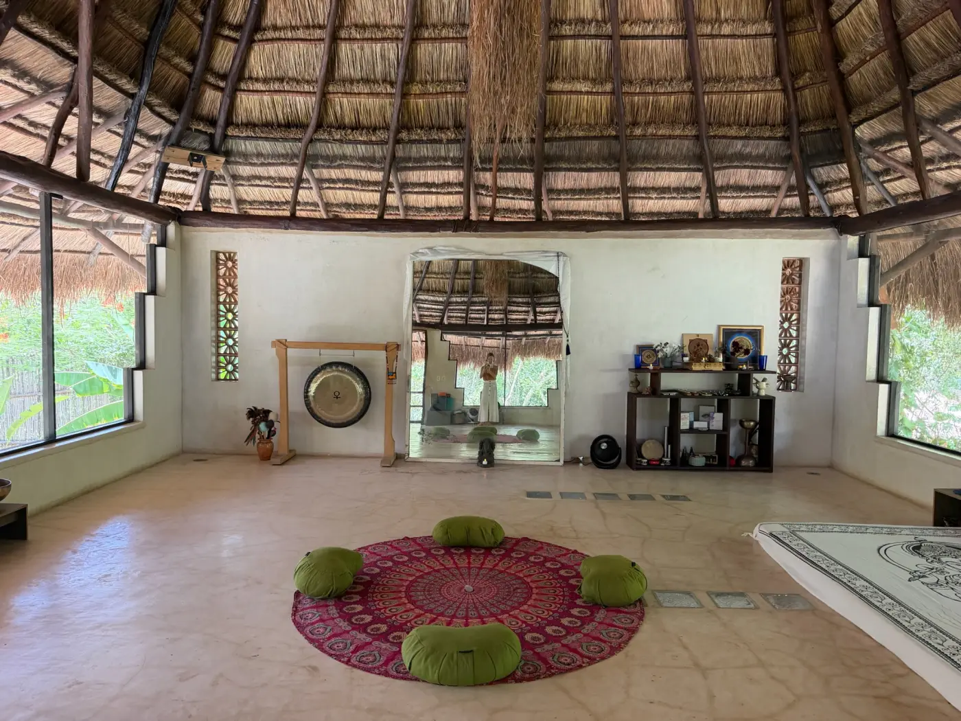 The sanctuary's open-air meditation and yoga studio, with a circular red rug, cushions, and a gong